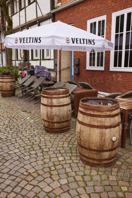 Old wine or beer barrels as decoration and a parasol with Veltins advertising in the outdoor area of a catering establishment in Warendorf, Warendorf district, North Rhine-Westphalia, Germany, Europe