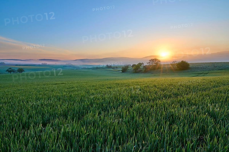 A picturesque sunrise over a wide green field and a gentle hilly landscape, Mönchberg, Mltenberg, Spessart, Bavaria, Germany, Europe