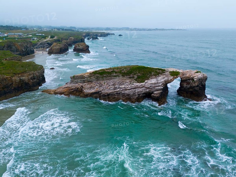 A striking rock in the shape of a natural bridge, surrounded by foaming waves and a tantalising coastline, aerial view, Praia das Catedrais, Playa de las Catedrales, As Catedrais beach, Cantabrian Sea, Ribadeo, Galicia, Galicia, Spain, Europe