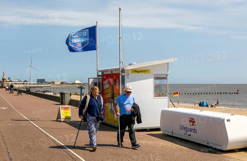People walking with sticks past Lifeguards station on the Esplanade, Lowestoft, Suffolk, England, UK