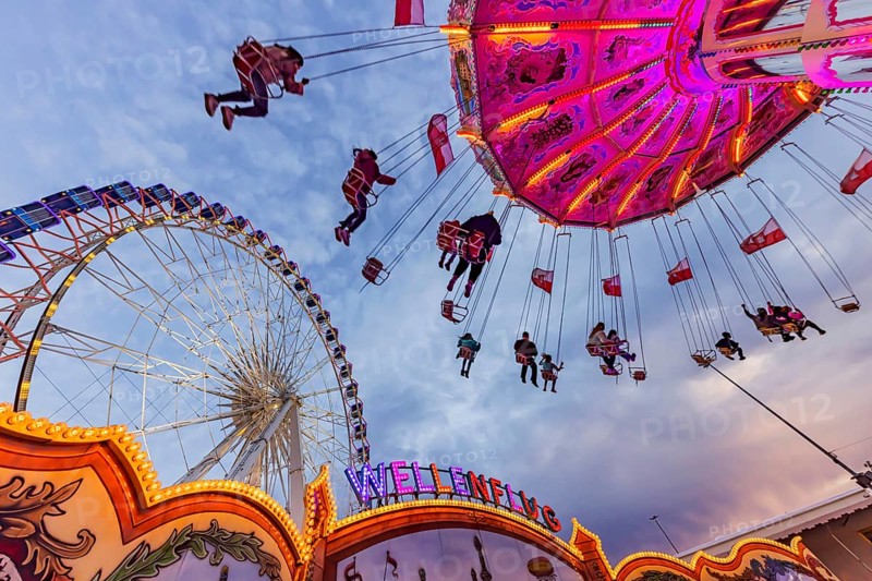 Chain carousel and Ferris wheel in the evening. 177th Cannstatter Volksfest at the Cannstatter Wasen. Bad Cannstatt, Stuttgart, Baden-Württemberg, Germany, Europe