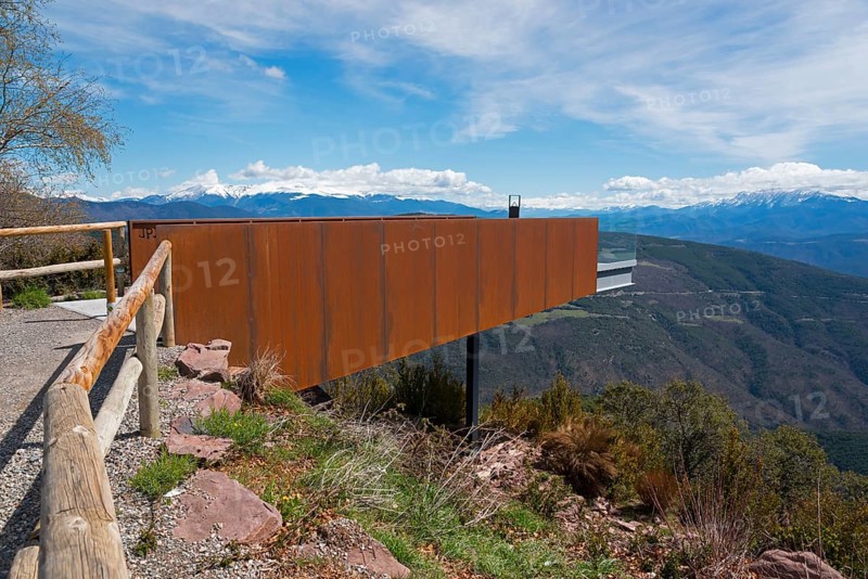 Aussichtsplattform aus rostfarbenem Metall und Holzgeländer mit weiten Blick auf die Berge und den blauen Himmel, Aussichtspunkt des Creu de Guils, in der Nähe der N-260, Lleida, Katalonien