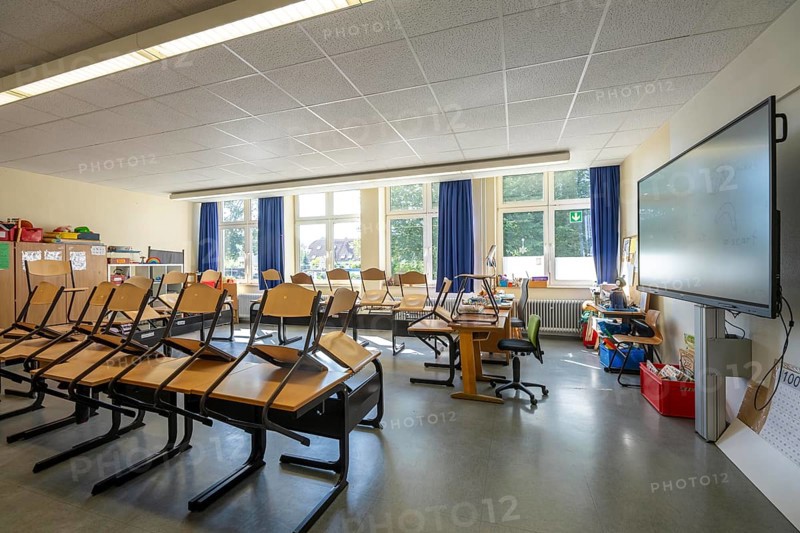 Classroom of a fourth grade, after school, the building is older but in good condition, modern teaching materials, interactive, digital whiteboard