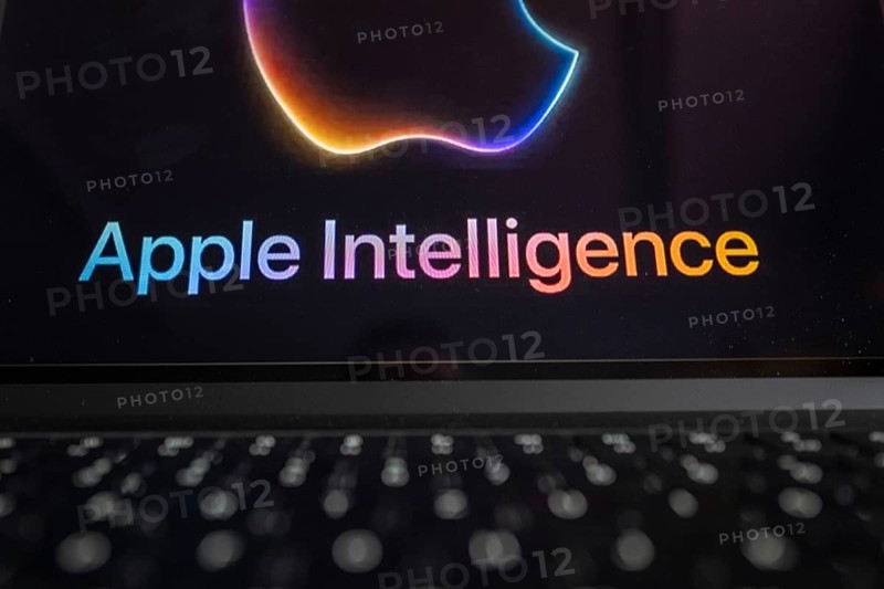 Apple logo in bright neon colours on a Macbook with illuminated keyboard and the text 'Apple Intelligence' underneath, symbolic image of artificial intelligence