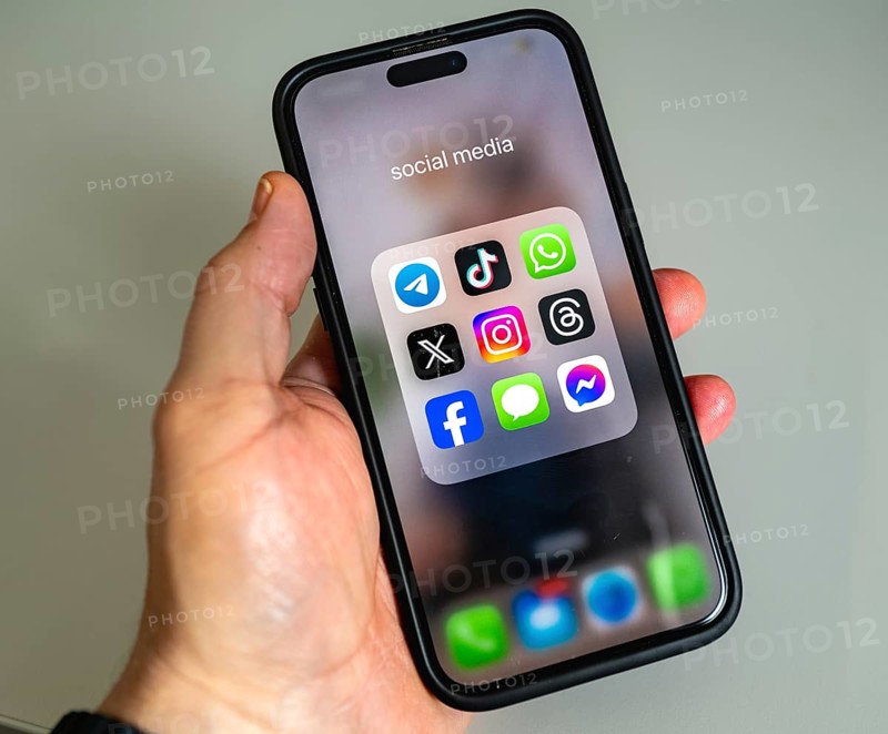 A smartphone is held in the hand and shows app icons, display on a screen, WhatsApp, Tik Tok, X, Facebook and Messages app, instant messenger service, social networks
