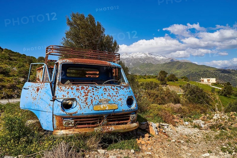 Abandoned rusty blue car on a green field with mountains in the background, wrecked vehicle, Crete, Greek Islands, Greece, Europe