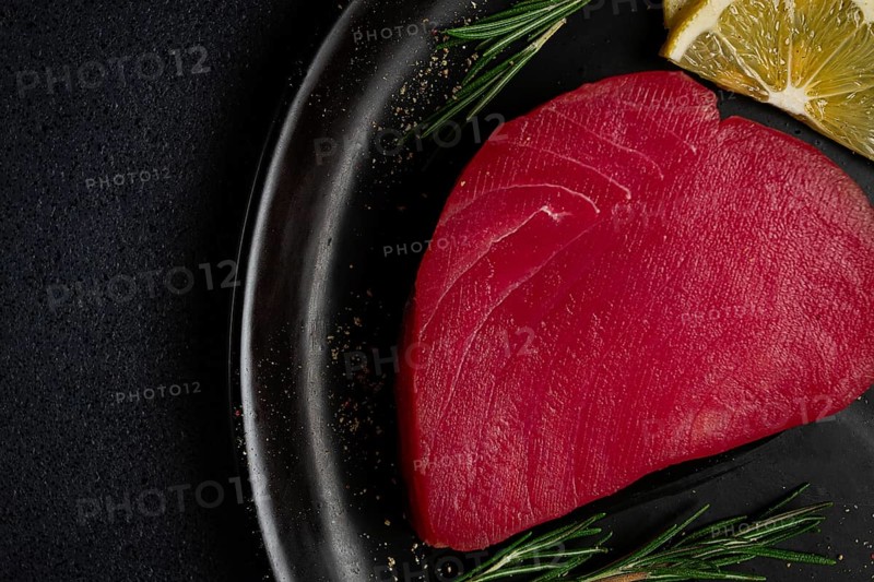 Fresh red tuna fillet, for steak, raw, top view, on a black plate, no people