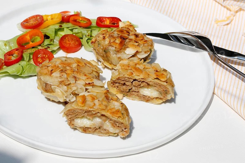 Swabian cuisine, meatballs wrapped in almonds, mixed minced meat, meatballs filled with cheese, fried, meatballs, grandmother's cooking, regional, home cooking, typical Swabian, traditional cuisine reinterpreted, served on a plate with salad, lettuce, cherry tomatoes, cocktail tomatoes, peppers, food photography, studio, Germany, Europe