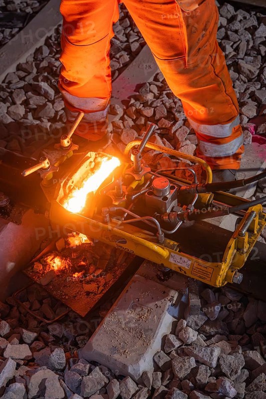 Mechanical device working on rails, surrounded by sparks, protective clothing, rail welding, track construction Hermann Hessebahn, Calw, Black Forest, Germany, Europe