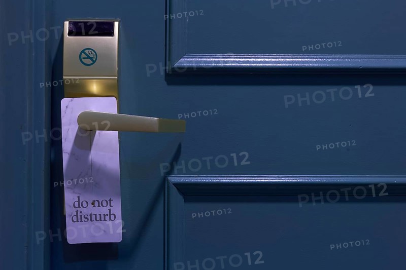 Blue painted door with 'Do Not Disturb' sign and gold-coloured handle in a hotel