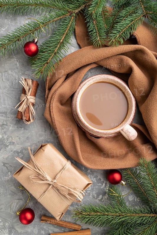 Christmas or New Year composition. Decorations, box, cinnamon, fir and spruce branches, cup of coffee, wool scarf on a gray concrete background. Top view, close up, flat lay