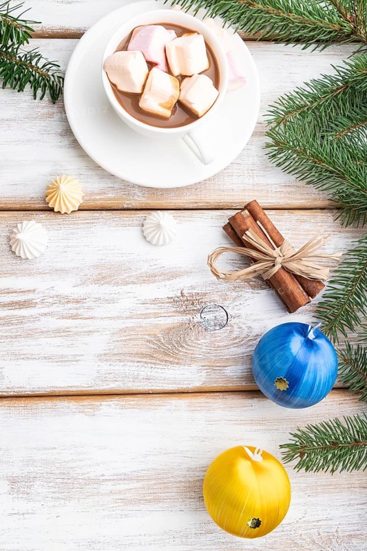 Christmas or New Year frame composition. Decorations, box, balls, cinnamon, ribbons, fir and spruce branches, cup of coffee, on a white wooden background. Top view, copy space, flat lay