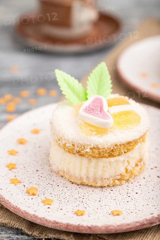 Decorated cake with milk and coconut cream with cup of coffee on a gray wooden background and linen textile. Side view, close up, selective focus