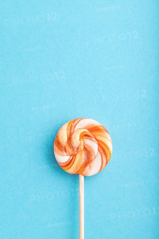 Single lollipop candy on blue pastel background. copy space, top view, flat lay