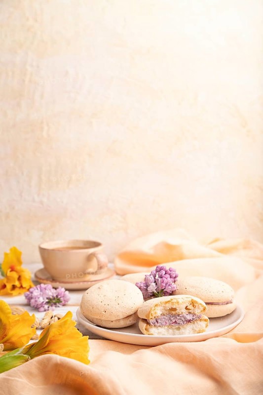 Meringues cakes with cup of coffee on a white background and orange linen textile. Side view, copy space, selective focus