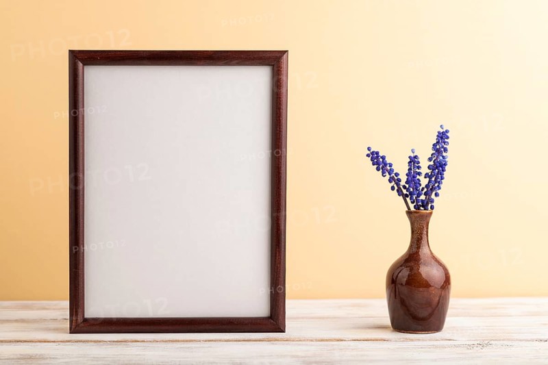 Wooden frame with blue muscari hyacinth flowers in ceramic vase on orange pastel background. side view, copy space, still life, mockup, template, spring, summer minimalism concept