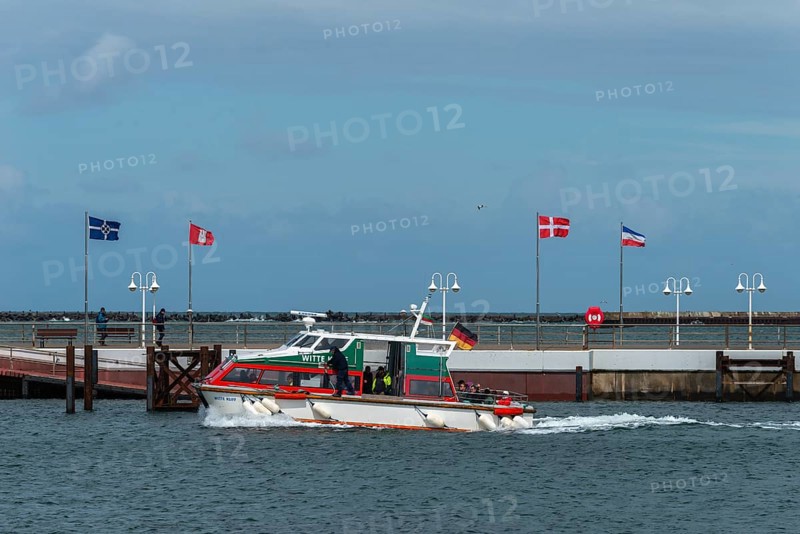 Dune ferry arrives in Heligoland harbour, flags in the wind, pier, offshore island of Heligoland, North Sea, Pinneberg district, Schleswig-Holstein, Germany, Europe