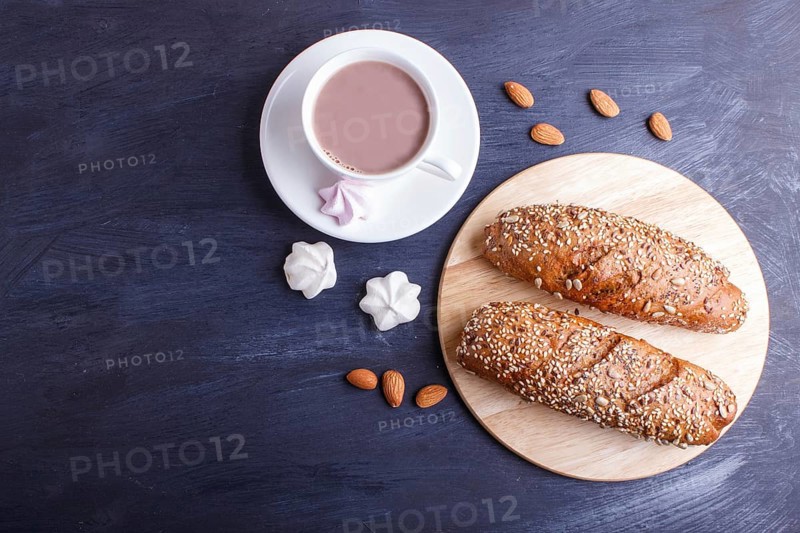 Rye bread with sunflower seeds, sesame and flax with cup of cocoa on dark blue background. top view, copy space