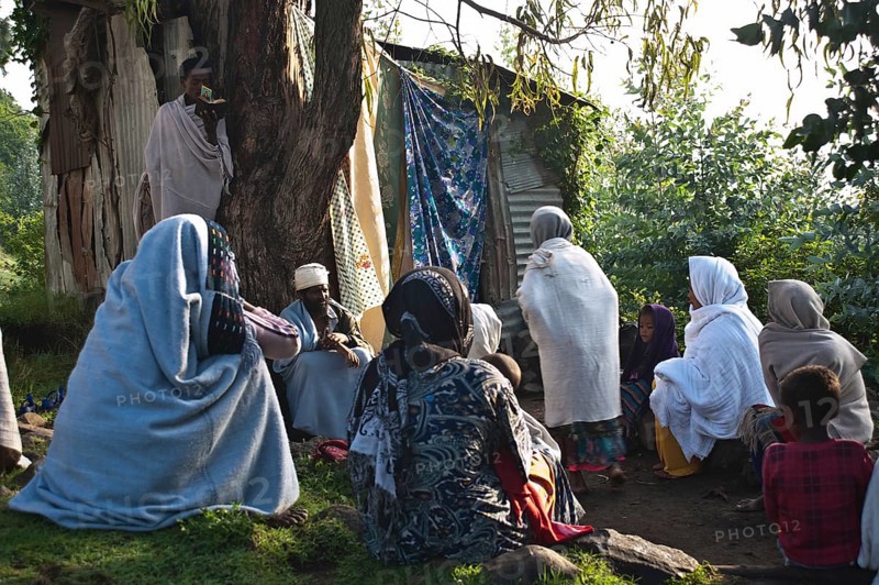 Orthodox christian persons waiting their turn to get rid of evil spirits, Tigray state, Ethiopia. Many orthodox christians believe problems are due to evil spirits. So they go to the local orthodox church compound where there is a makeshift space dedicated to this function. Once inside, they wash their body with holy water. The monk controls that everything works correctly while his aide reads holy scriptures
