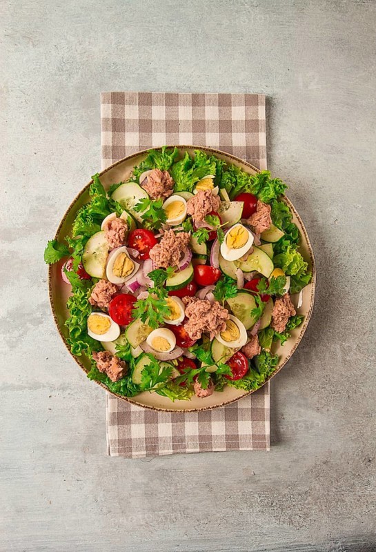 Tuna salad, vegetable salad with quail eggs, lettuce, red onion and cucumbers, on a light gray table, keto food, lifestyle, healthy eating, selective focus, top view, no people