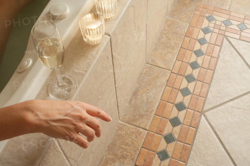 Woman relaxing in the bathroom spa tub with a glass of sparkling champagne and candles