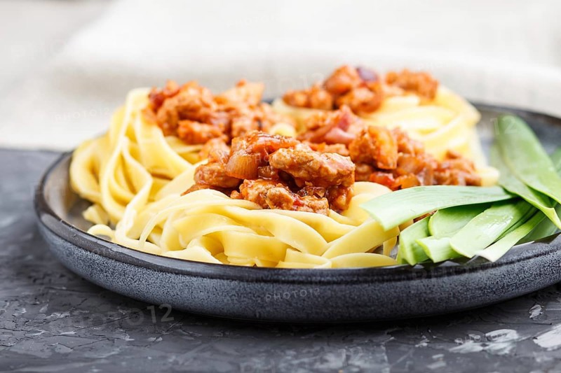 Tagliatelle bolognese pasta with minced meat on a black concrete background. side view, close up