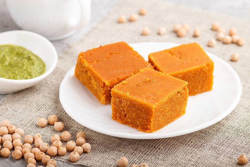 Traditional indian candy burfi in white plate with mint chutney on a gray concrete background. side view, close up