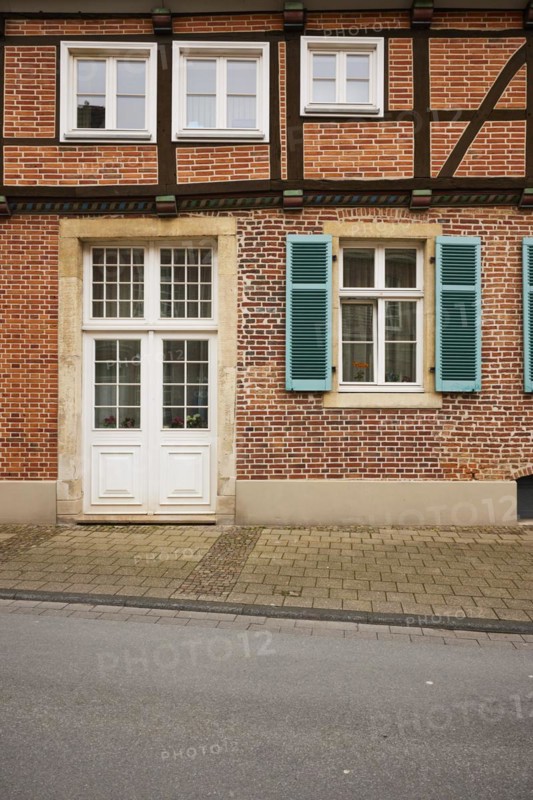 White entrance door and windows with blue-green shutters on a brick house in Warendorf, Warendorf district, North Rhine-Westphalia, Germany, Europe