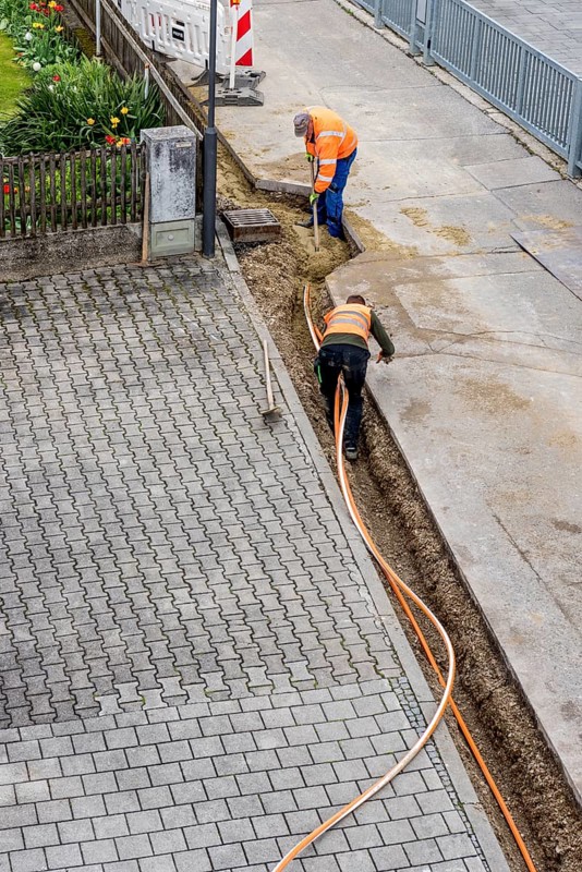 Construction workers lay fibre optic cable in trench under asphalt, cable trench, construction site, fibre optic expansion, fast internet, residential area, rural, village, Marzling, Upper Bavaria, Bavaria, Germany, Europe