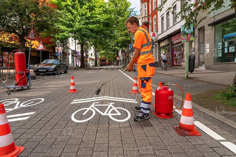 Application of road markings for a cycle lane, Rüttenscheider Straße in Essen, in the shopping and gastronomy district, cyclists have right of way over motorised vehicles, part of a cycle axis through Essen's city centre