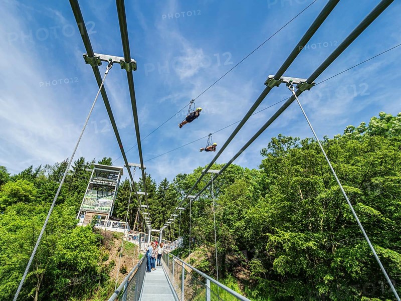 Rappbode water reservoir, suspension bridge Titan RT, two tourists 'flying' above the bridge on the mega-zipline, Rappbode, Harz, Germany, Europe