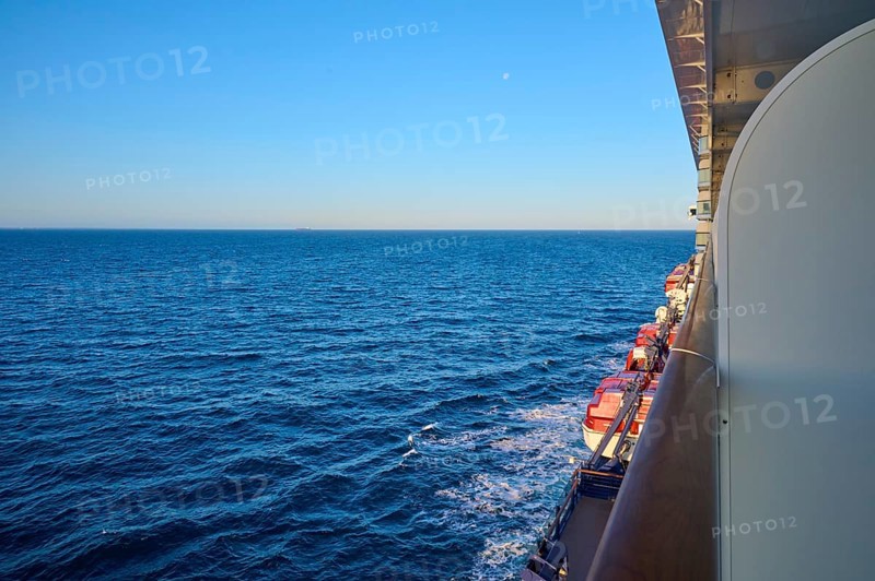 A large ship sails calmly on the blue ocean under a clear sky, with a view of the lifeboats from the balcony, North Sea, Denmark, Europe