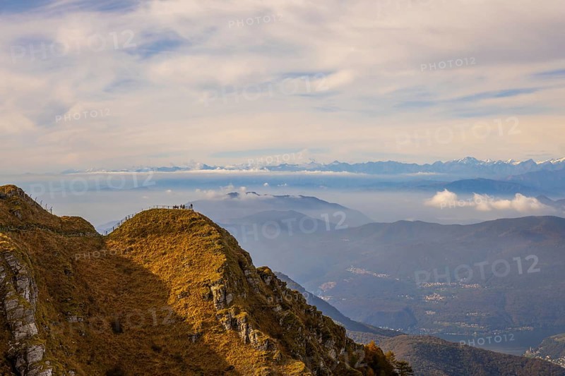 Aerial View over a Beautiful Mountainscape and a Mountain Peak with People and with Floating Clouds in a Sunny Day in Ticino, Switzerland, Europe