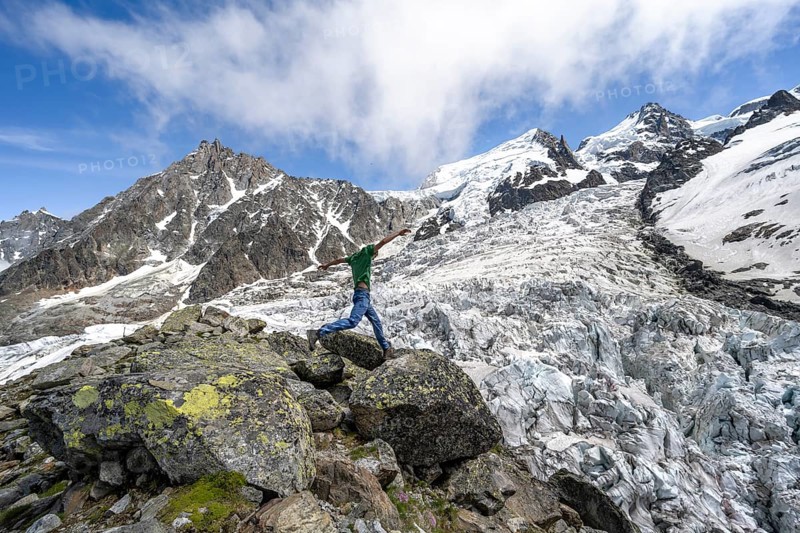 Mountaineer jumping from rock to rock, high alpine glaciated mountain landscape, La Jonction, Glacier des Bossons meets Glacier de Taconnaz, summit of Aiguille du Midi, Mont Maudit and Mont Blanc, Chamonix, Haute-Savoie, France, Europe
