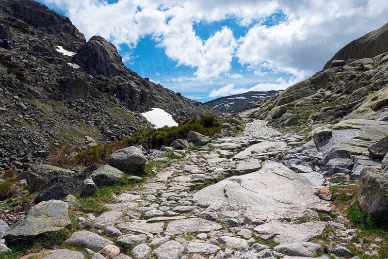 A stony path winds its way through a rocky mountain landscape under a cloudy sky, hiking area, Reserva national de Gredos, Garganta de Prado Puerte, Prado Puerte Gorge, Sierra de Gredos, Ávila, Avila, Madrid, Spain, Europe