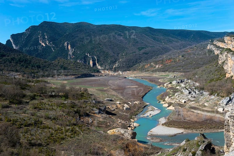 A winding river through a wide valley, surrounded by wooded mountains and rocks under a clear sky, Noguera Ribagorçana Mont-rebei Natural Park, Montsec mountain range, Noguera Ribagorçana river, Lleida province, Catalonia, Aragon, Spain, Europe
