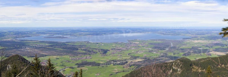 Panoramic view over a green landscape with mountains in the foreground and the large Chiemsee in the distance, photographed from the Hochgern summit, in Bavaria Germany Europe
