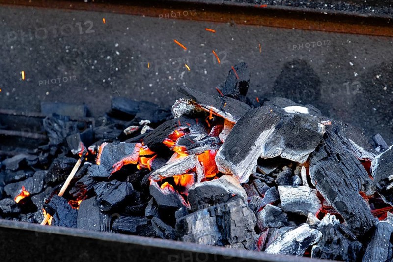 Hot glowing charcoal with sparks and flames, ready for grilling