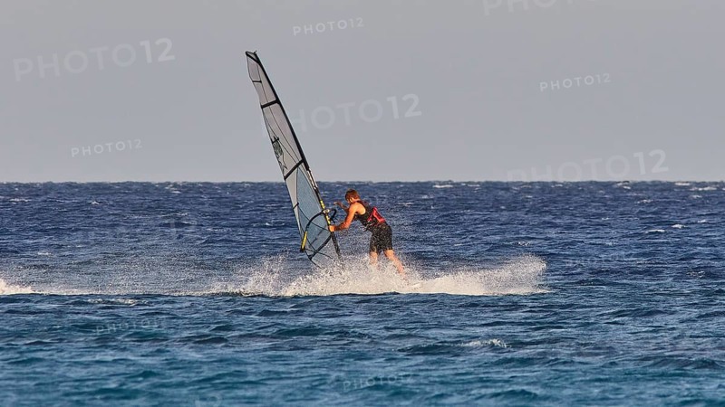 A windsurfer navigates with a big sail over the blue water, windsurfer, Meltemi windsurfing spot, Devils Bay, Paralia Vatha, Vatha Beach, south-east coast, Karpathos, Dodecanese, Greek Islands, Greece, Europe