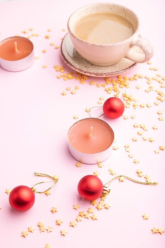 Christmas or New Year composition. Decorations, red balls, cup of coffee, on a pink paper background. Side view, copy space
