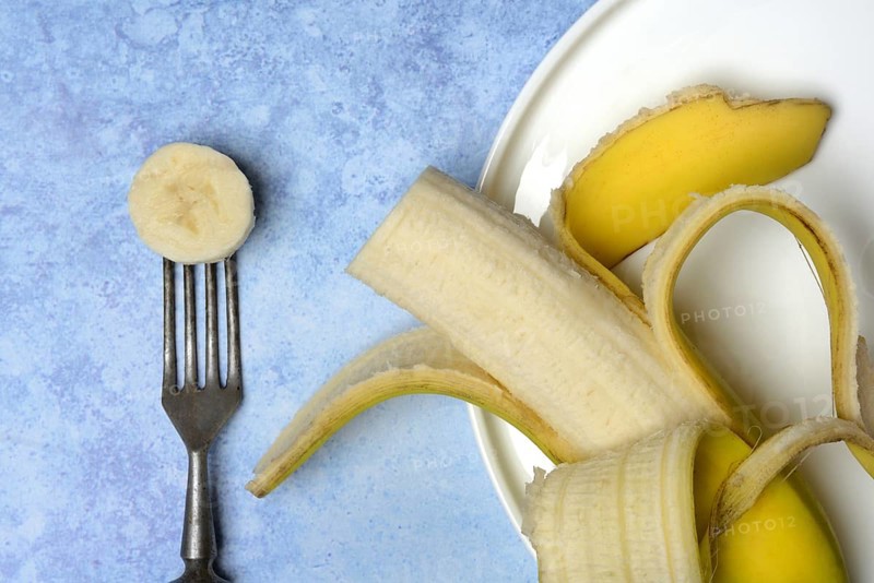 Opened banana on plate and fork with banana slice