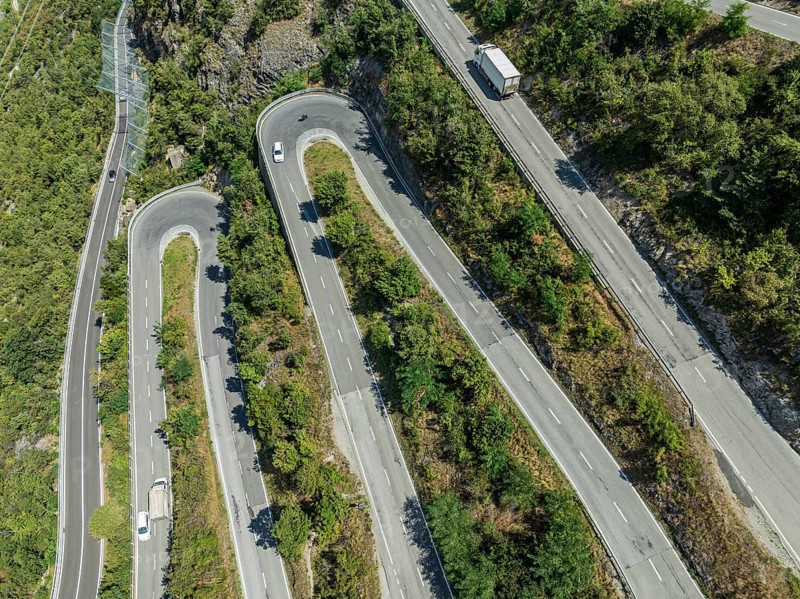 Mountain pass road with multiple hairpins, water pipeline, aerial view, drone shot. Valais, Switzerland, Europe