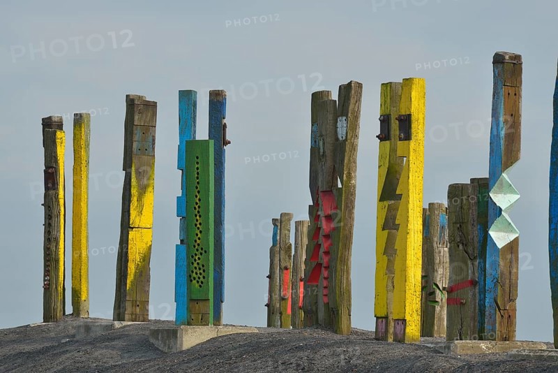 A creative art installation of colourfully painted wooden posts with abstract patterns against a grey sky, Haniel slagheap, Bottrop, Oberhausen, Ruhr area, North Rhine-Westphalia, Germany, Europe