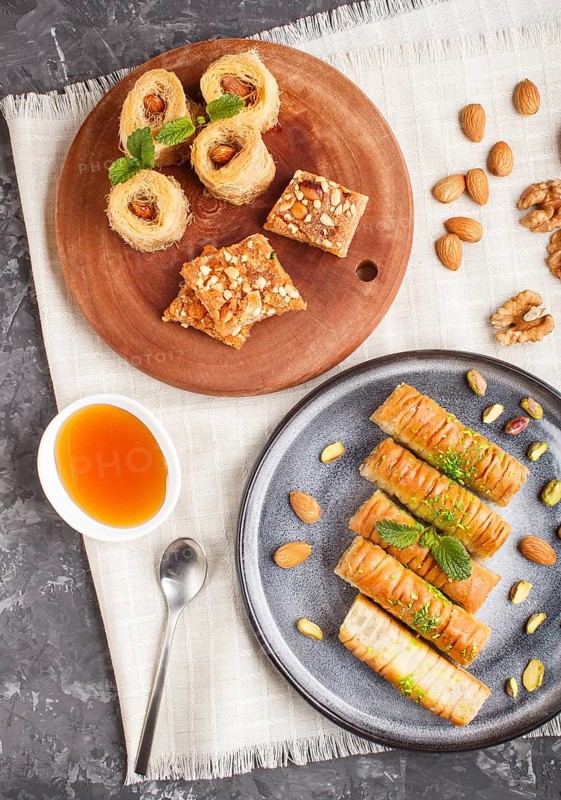 Set of various traditional arabic sweets: baklava, kunafa, basbus in ceramic plates on a black concrete background. top view, flat lay