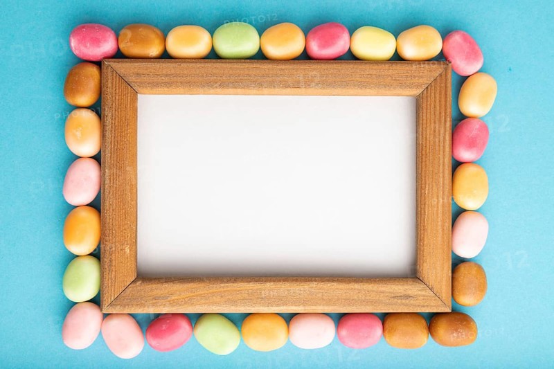 Composition with candies and wooden frame on blue pastel background. copy space, top view, flat lay, template