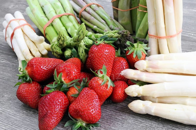 Green asparagus, white asparagus and fresh strawberries decorated on a rustic wooden table