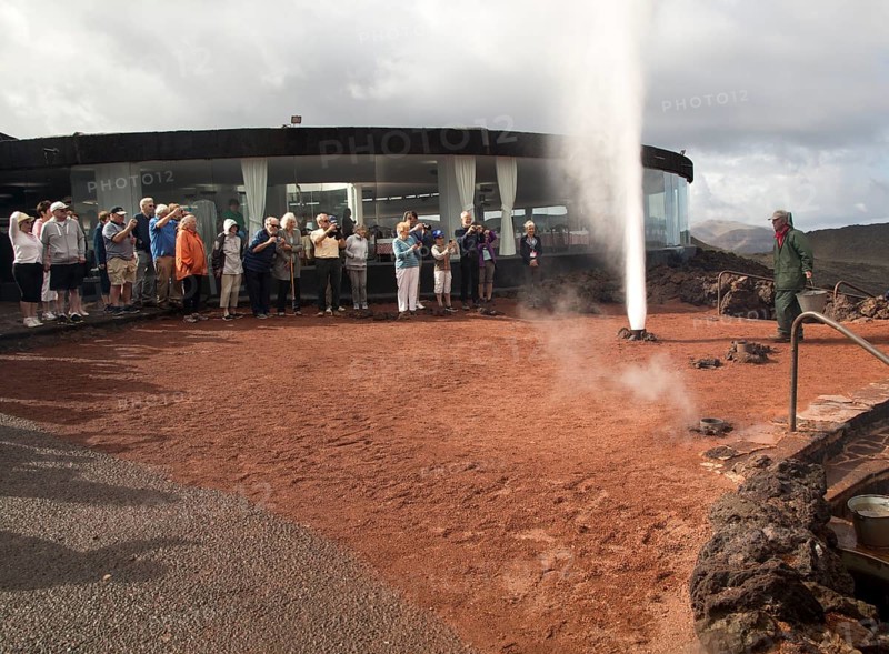 Tourists watch steam rise from geyser spout, Parque Nacional de Timanfaya, national park, Lanzarote, Canary Islands