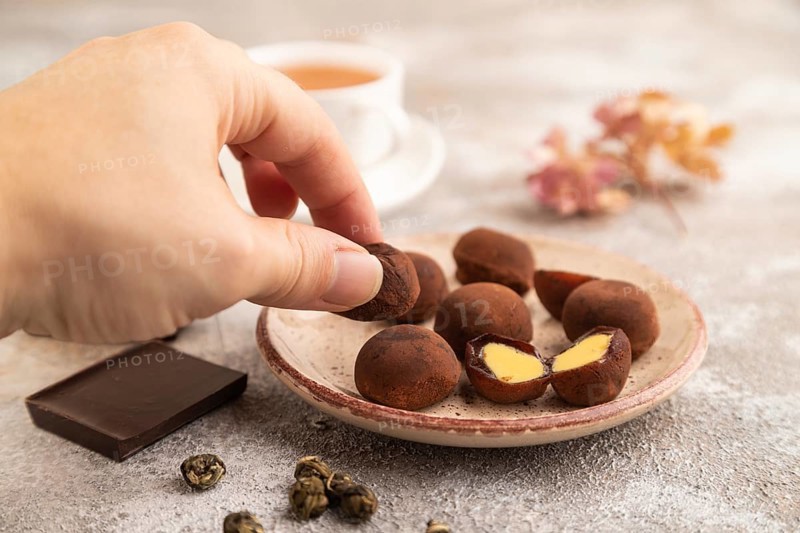 Japanese rice sweet buns chocolate mochi filled with cream and cup of green tea and hand on brown concrete background. side view, close up, selective focus