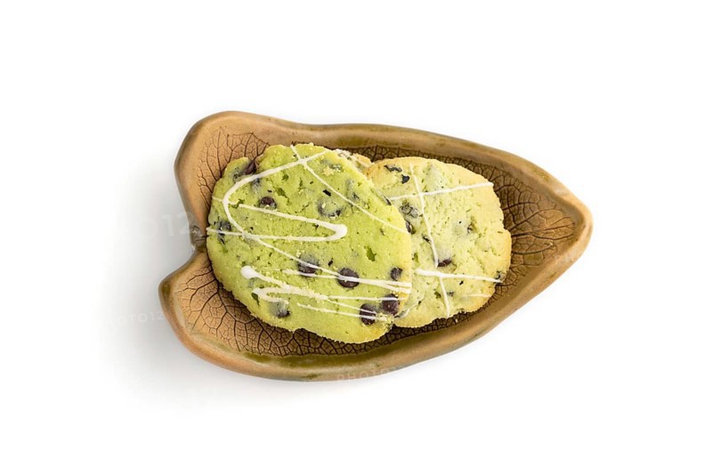Green cookies with chocolate and mint on leaflike ceramic plate isolated on white background. top view, flat lay, close up