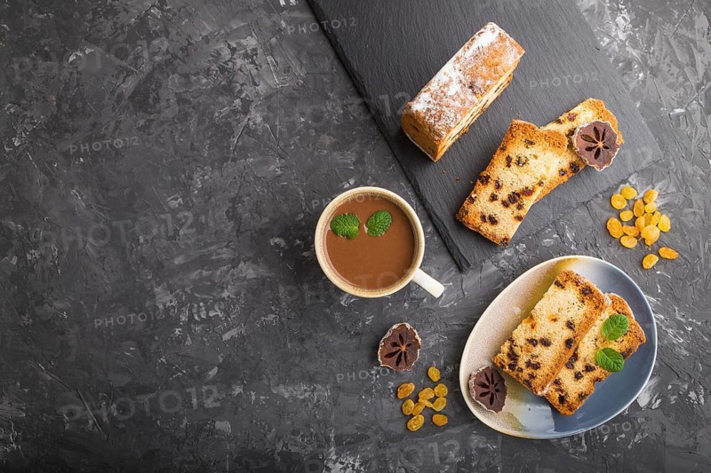 Homemade cake with raisins, dried persimmon and a cup of hot chocolate on a black concrete background. top view, flat lay, copy space